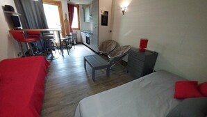 Een hotelkamer met een bed, een bureau met stoelen, een bijzettafeltje, een stoel en een kledingkast.