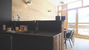 Uma cozinha moderna com uma parede de madeira, uma pia e um espaço de refeições com cadeiras e mesa.