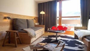 Um quarto aconchegante com cabeceira de madeira, um sofá, uma mesinha com abajur e vista para o exterior.