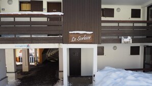 Hotellin sisäänkäynti, jossa on kyltti, jossa lukee ”Le Sorbier”, ja katettu käytävä, joka johtaa sisäänkäynnille.