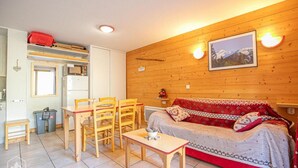 Une pièce chaleureuse avec un mur en bois, un canapé, une table et des chaises.