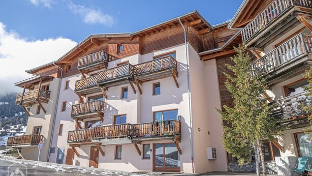 Un hôtel à plusieurs étages, doté de balcons en bois et surplombant un paysage montagneux.