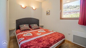 Une chambre à coucher avec un lit, deux lampes de chevet, une fenêtre donnant sur un beau paysage et un tableau accroché au mur.