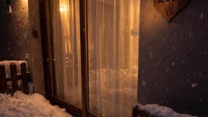 Un banc recouvert de neige et une porte coulissante en verre ornée d’un panneau en forme de cœur sur lequel est inscrit le numéro 2165.