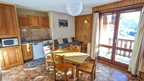 A cozy kitchen with wooden cabinets, a dining table, and a sofa. - 10m from ski slopes, floor -1, balcony, tv, 31m², Aussois (Aussois)