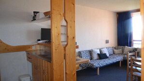 A compact room with a kitchenette, a sofa, and a window with curtains. - 50m from resort center, 1st floor, view mountain, balcony, tv, 33m², Les Arcs (Les Arcs)