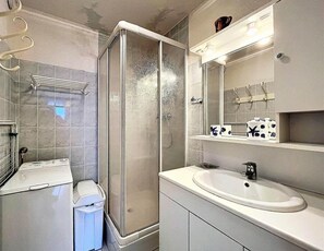 Ein Badezimmer mit einer Duschkabine, einem Waschbecken und einem Spiegel.