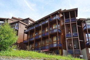 Een meerlaags gebouw met balkons, een houten gevel en een bord waarop 