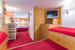 A compact room with a bed, a television, a wooden wardrobe, and a small desk with a lamp. - 300m from resort center, 3rd floor, balcony, tv, 35m², Les Arcs (Les Arcs)