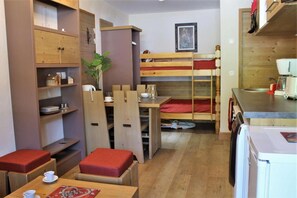 A compact room with bunk beds, a kitchenette, and a dining area with a table and chairs. - 300m from resort center, 4th floor, view ski slopes, swimming pool, sauna, balcony, tv, ski locker (Risoul)