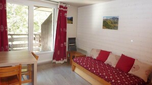 A room with a wooden bed, a dining table with chairs, and a window with curtains. - 300m from ski slopes, 5th floor, view forest, balcony, tv, 38m², Les Orres (Les Orres)