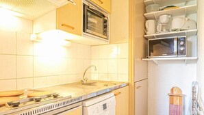 A compact kitchen with a stove, sink, and microwave. - 3rd floor, balcony, tv, 30m², Aussois (Aussois)