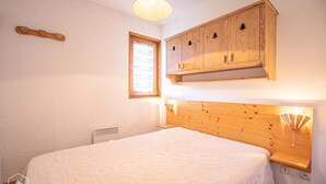 A bedroom with a wooden headboard, a window with blinds, and a wooden cabinet above the bed. - 3rd floor, balcony, tv, 30m², Aussois (Aussois)