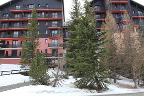 Ein mehrstöckiges Gebäude mit Balkonen, umgeben von Schnee und Bäumen.