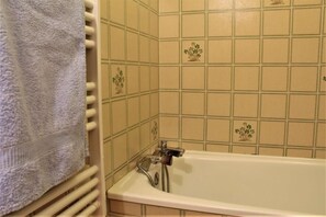 Ein Badezimmer mit Badewanne, Handtuchhalter und Wänden mit floralem Muster.