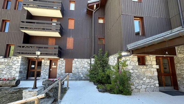 Un bâtiment moderne doté de nombreux balcons, de murs en pierre et d’une cour dallée.