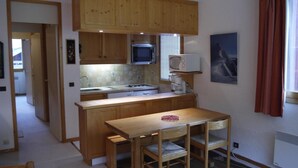 Une cuisine compacte avec des meubles en bois, un four à micro-ondes et une petite table à manger avec des chaises.