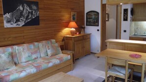 Une pièce chaleureuse avec un mur en bois, un canapé, une petite table et un coin cuisine.