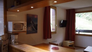 Une cuisine compacte équipée d’un four à micro-ondes, d’une machine à café et d’une petite table.