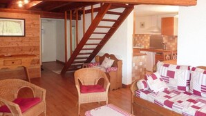 A cozy room with a wooden staircase, wicker furniture, and a patterned sofa.