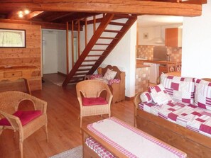 A cozy living area with wicker furniture, a wooden staircase, and a kitchenette.