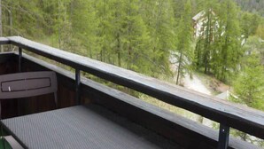 A balcony with a view of a forested area and a building in the distance.