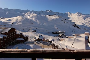A snow-covered mountain resort with ski slopes, a ski lift, and buildings with snow-covered roofs.