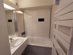 Ett badrum med ett vitt handfat, en spegel och en duschavdelning med glasväggar.