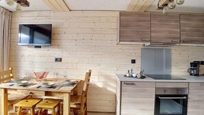 A modern kitchen with wooden cabinetry, a built-in oven, and a flat-screen TV mounted on the wall. - Ground floor, view exceptional, balcony, tv, ski locker, 24m², Les Menuires (Les Menuires)
