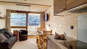 A cozy cabin interior with a living area, dining table, and kitchen. - Ground floor, view exceptional, balcony, tv, ski locker, 24m², Les Menuires (Les Menuires)
