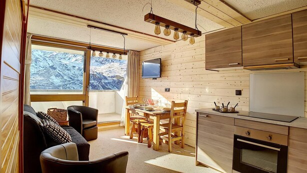 A cozy cabin interior with a dining area, kitchen, and seating space. - Ground floor, view exceptional, balcony, tv, ski locker, 24m², Les Menuires (Les Menuires)
