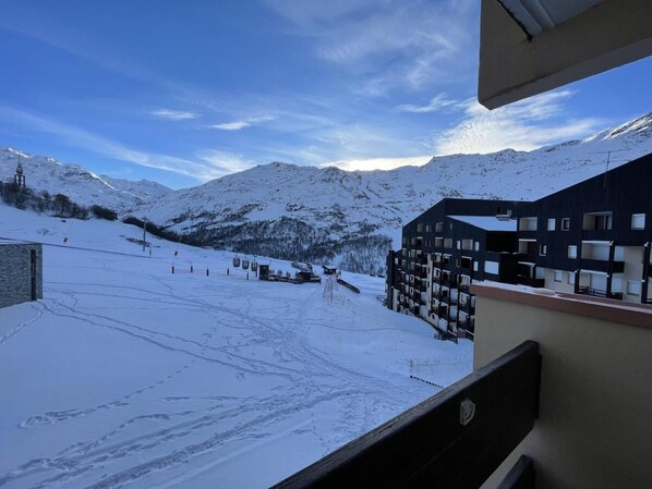 A snow-covered ski slope with a building in the foreground.