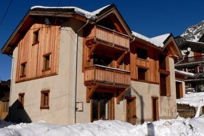 A wooden chalet with balconies, a ski lift in the background, and snow on the roof. - 1st floor, balcony, parking, tv, 32m², Pralognan-la-Vanoise (Pralognan-la-Vanoise)