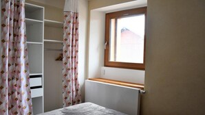 A bedroom with a window, a radiator, and a wardrobe.