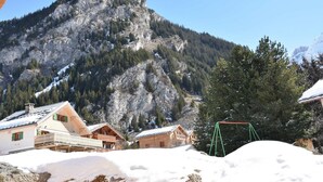 A mountain lodge with wooden cabins, a ski lift, and snow-covered surroundings.