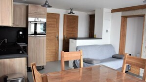 A compact kitchen with wooden cabinets, a built-in oven, and a dining area with a table and chairs.