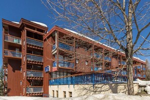 Um hotel com várias andares, varandas e telhado coberto de neve.
