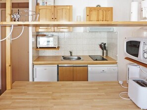 A compact kitchen with a wooden countertop, a built-in dishwasher, a microwave, and a toaster. - 15m from ski slopes, 6th floor, view ski slopes, balcony, 28m², Les Orres (Les Orres)