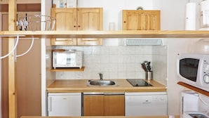Eine kleine Küche mit Holzausstattung, einer eingebauten Mikrowelle, einem Toaster und einem Geschirrspüler.