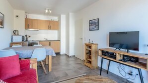 A compact living space with a kitchenette, a dining area, a TV, and a red sofa. - 50m from ski slopes, 4th floor, view mountain, balcony, tv, ski locker, 36m², La Plagne (La Plagne)