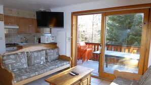 A living room with a sofa, a coffee table, and a TV. There is a sliding glass door leading to an outdoor area with a table and chairs. - 200m from resort center, Ground floor, terrace, tv, ski locker, 72m², Champagny-en-Vanoise (Champagny-en-Vanoise)