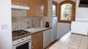 A compact kitchen with wooden cabinets, a gas stove, a sink, a coffee maker, and a refrigerator. - 200m from resort center, Ground floor, terrace, tv, ski locker, 72m², Champagny-en-Vanoise (Champagny-en-Vanoise)