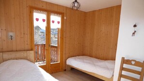 A wooden room with two beds, a chair, and a balcony with a view. - 200m from resort center, Ground floor, terrace, tv, ski locker, 72m², Champagny-en-Vanoise (Champagny-en-Vanoise)