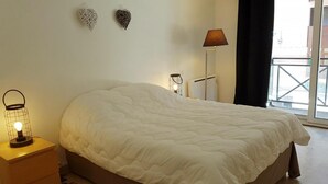 Ein Schlafzimmer mit einem großen Bett, einem Nachttisch mit Lampe und dekorativer Wandkunst.