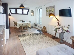 Un salon moderne comprenant un coin repas, une grande fenêtre, un téléviseur à écran plat et une lampe décorative.
