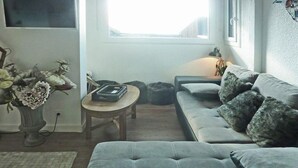 A living room with a grey sofa, a small round table, a vase of flowers, and a window with a view. - Ski-in/ski-out & foot of the slopes, 3rd floor, view valley, terrace, tv, ski locker, 55m² (Les Orres)