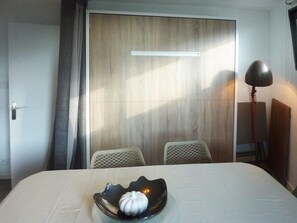 A hotel room with a bed, a bedside table with a lamp, a wooden door, and a view of the outside. - Ski-in/ski-out & foot of the slopes, 3rd floor, view valley, terrace, tv, ski locker, 55m² (Les Orres)