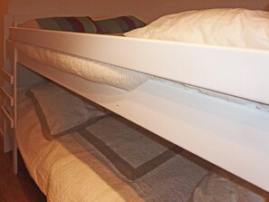 Un lit superposé avec un lit en bas et un matelas posé sur le sol.