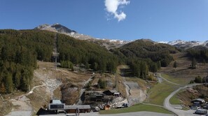 Un paysage montagneux avec un télésiège, une route et des bâtiments.