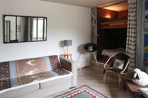 A cozy room with a sofa, a chair, a lamp, and a bed.